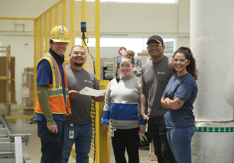 Group of coworkers collaborating in manufacturing plant.