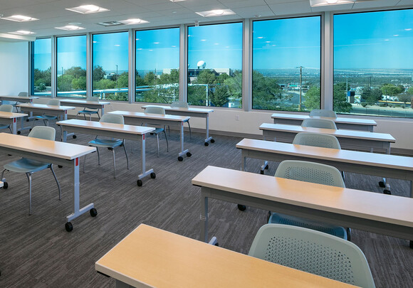 Classroom with individual desks in a room with smart glass windows overlooking the town. 